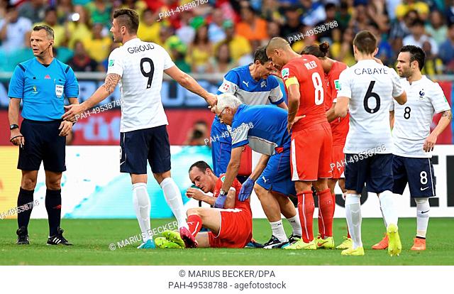 Steve von Bergen (C) of Switzerland lies injured on the pitch during the FIFA World Cup 2014 group E preliminary round match between Switzerland and France at...