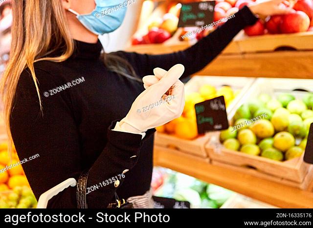 Kundin mit Einweghandschuhen wegen Covid-19 im Supermarkt beim Obst einkaufen