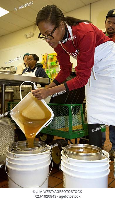 Detroit, Michigan - Volunteers filter honey they've extracted from honeycombs at Earthworks Urban Farm, a program of the Capuchin Soup Kitchen