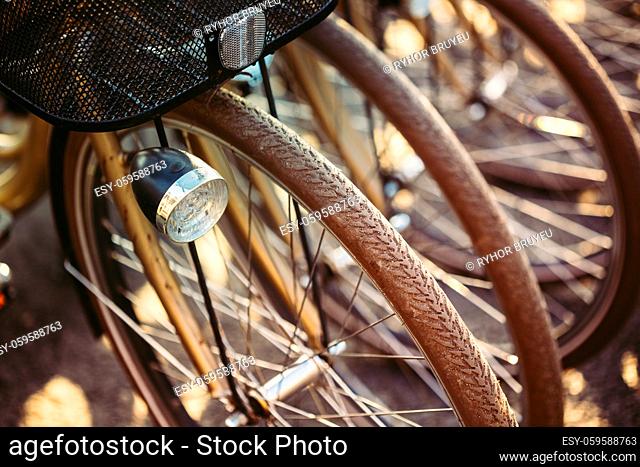 Row of parked vintage bicycles bikes for rent on sidewalk. Close up of wheel and bicycle headlight