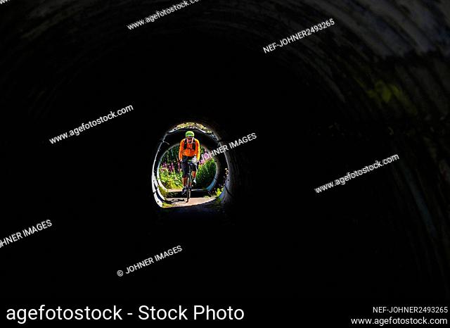 View of man cycling through tunnel