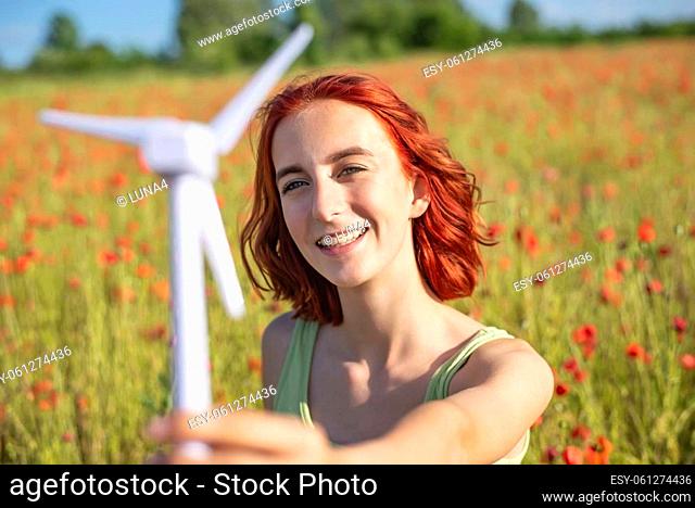 girl with wind turbine in poppy field