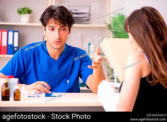 Young woman with bandaged arm visiting male doctor traumotologist