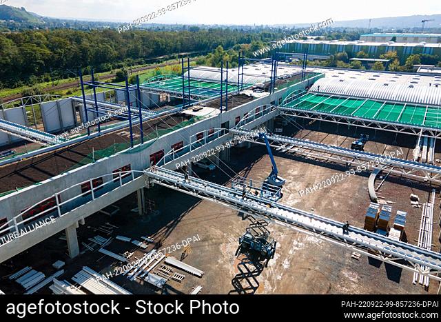 22 September 2022, Saxony, Radebeul: Construction vehicles stand on a building site for a new cardboard factory of the printing company Ellerhold (aerial view...