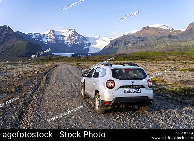 Car on gravel road, Vatnajökull glacier, mountains and wide landscape behind, Ring Road, Iceland, Europe