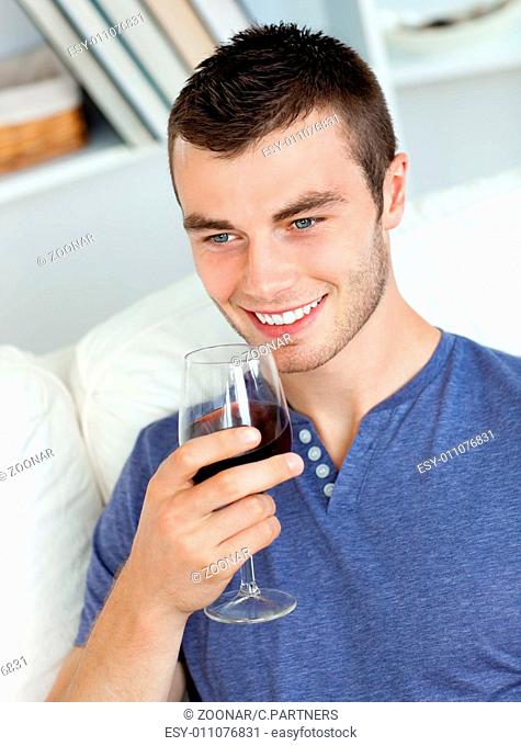 Animated young man drinking wine sitting on the sofa
