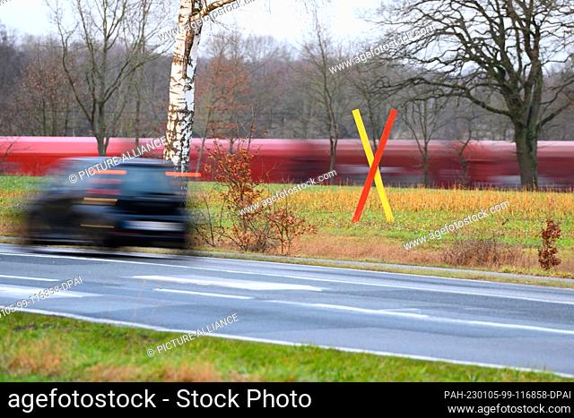 05 January 2023, Lower Saxony, Ramelsloh: A protest cross stands in a field near the planned new line and an existing route