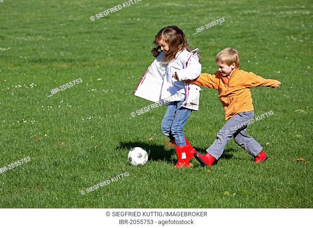 Girl and boy playing soccer