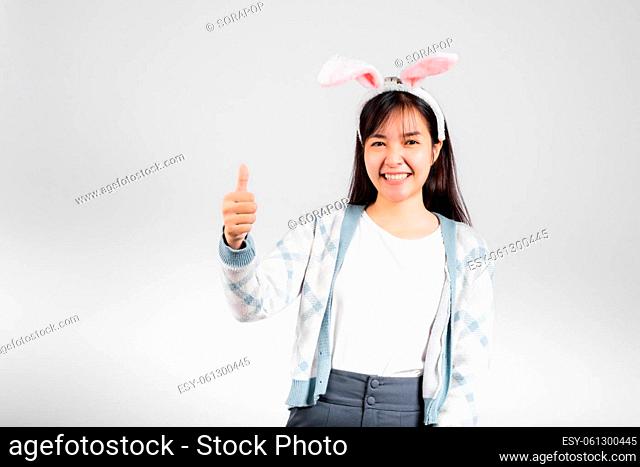 Easter day concept. Smiling happy woman wearing rabbit ears show thumb up for good sign, studio shot isolated on white background with copy space