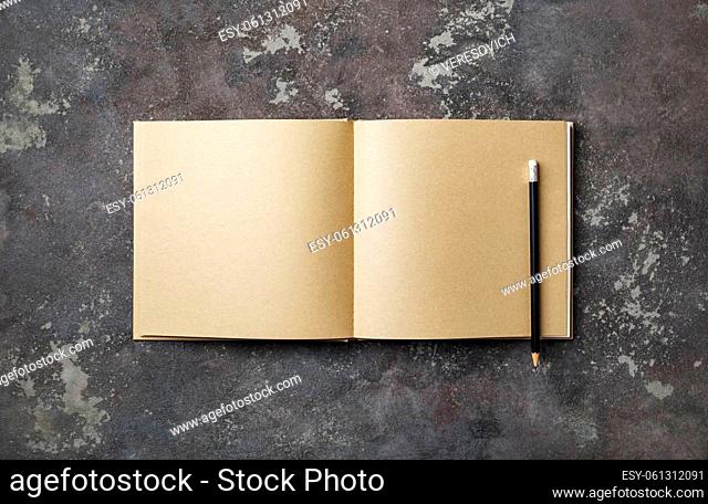 Blank kraft book and pencil on concrete background. Stationery elements. Template for placing your design. Flat lay