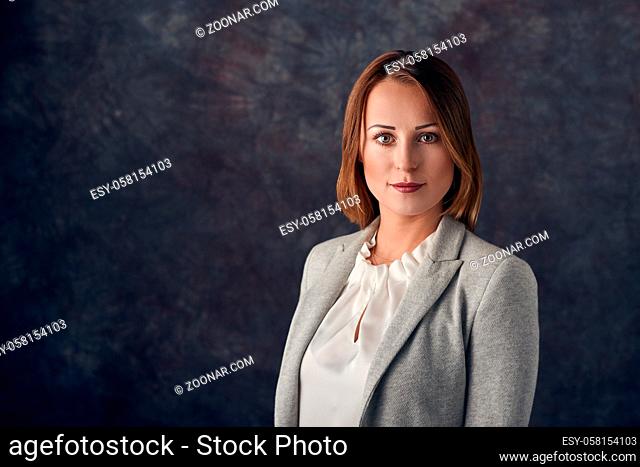 Portrait of smart elegant woman standing against dark background