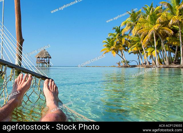 Feet and Hammock in tropical waters and Palapa platforms, North Long Coco Plum Caye, Belize