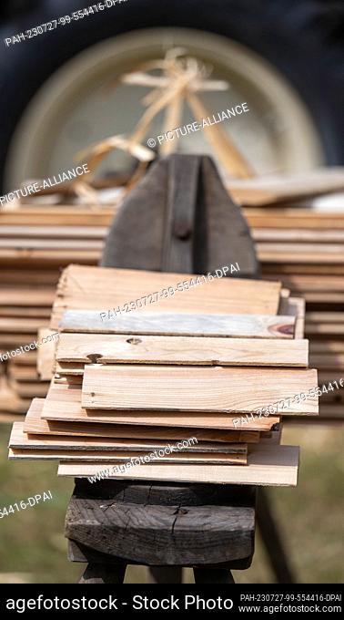 27 July 2023, Saxony, Seiffen: Wooden shingles lie on a trestle in front of the historic rafters' dwelling house in the Seiffen open-air museum