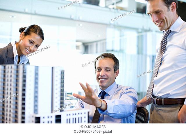 Architects looking at building model in office