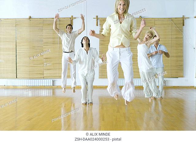 Group of adults in wellness center jumping into air