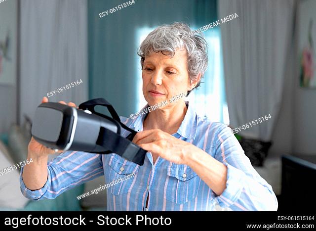 Senior Caucasian woman putting on a VR headset at home
