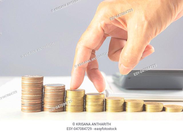Hand walking on stack coins on the table. Financial and growing