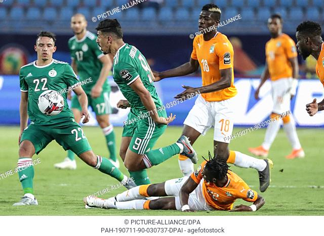 11 July 2019, Egypt, Suez: Cote d'Ivoire's Mamadou Bagayoko (bottom) and Algeria's Baghdad Bounedjah (C) Ismael Bennacer (L) battle for the ball during the 2019...