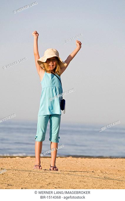 Glad girl, eight years, cheering at the beach