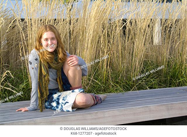 young woman about 20 years of age outdoors with grasses behind her