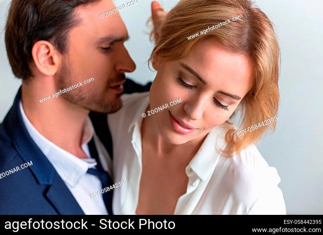 Businessman straightens hair of office worker sitting on his lap. Workplace romance. High quality photo