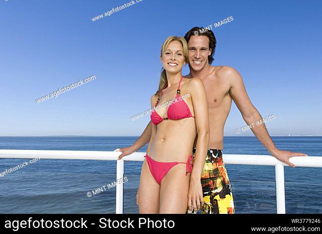Man and woman standing together at the rail of a cruise ship wearing swimwear