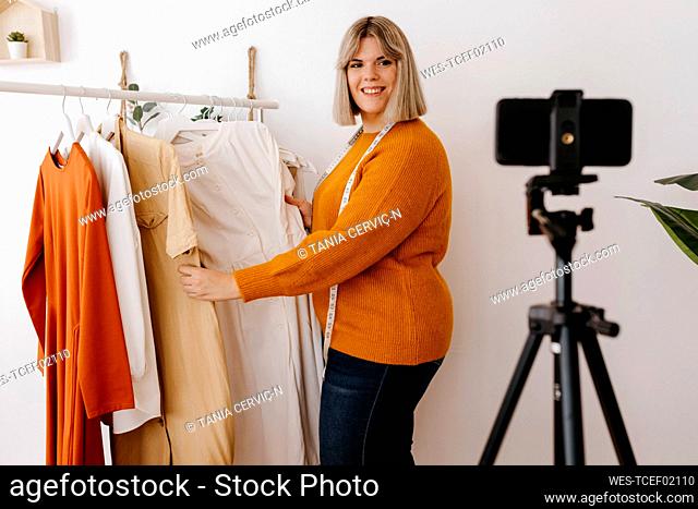 Smiling businesswoman showing dress on video call at creative office