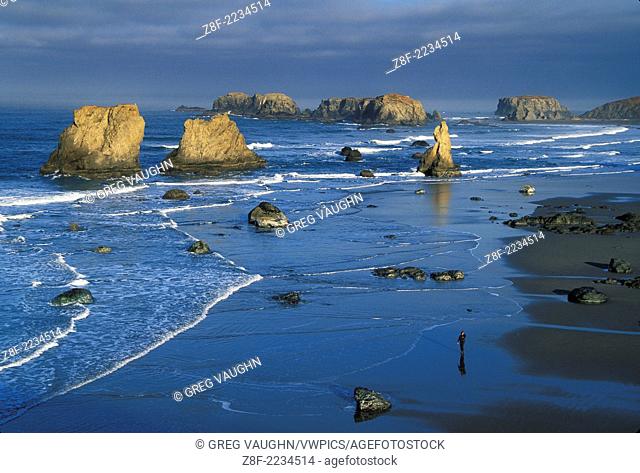 Bandon beach and sea stacks from Face Rock State Wayside, with woman walking on beach; Bandon, southern Oregon coast