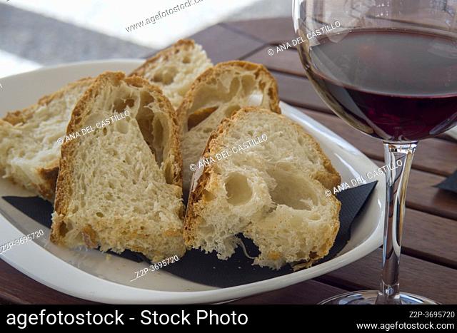 Glass of red wine and slices of homemade bread on plate in outdoor restaurant Spain