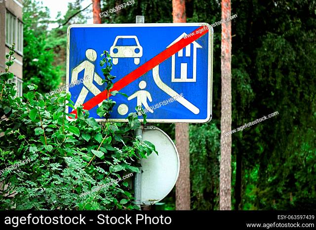 Sign of speed reduction near the local area crossed by red line standing near leafy hedge on blurred park background