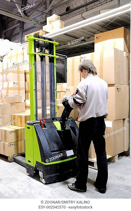 Operator of electric forklift stacker in warehouse