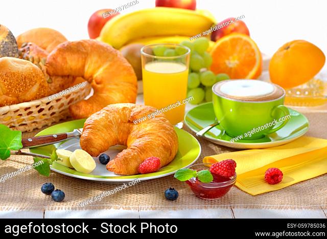 Gedeckter Frühstückstisch mit Croissants und Cappuccino - Breakfast table with a cup of cappuccino and fresh croissants