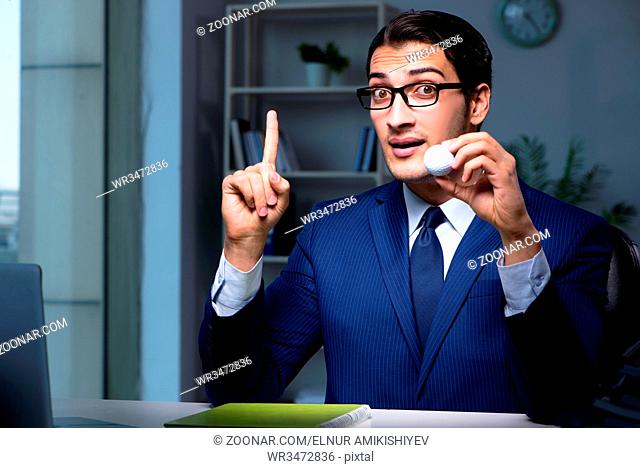 Young employee with golf ball in office