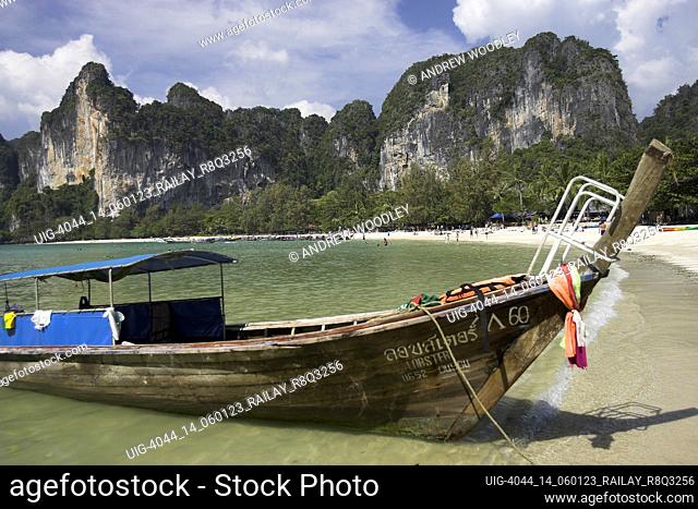Traditional longtail boat with sheer karst cliffs in background Railay Beach West Thailand