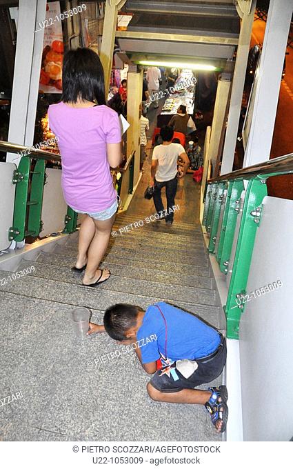 Bangkok (Thailand): a child begging along the staircase of the Nana subway station, along Sukhumvit Road