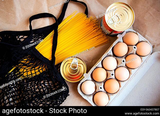 Packed eggs, canned food, pasta, products in an environmentally friendly bag on a background of ecological paper. Vegetarian healthy organic foods from the...