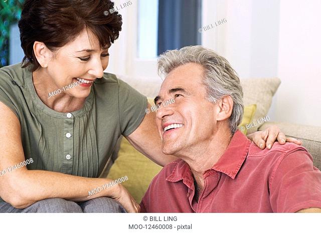 Middle-aged couple sitting smiling looking into eyes