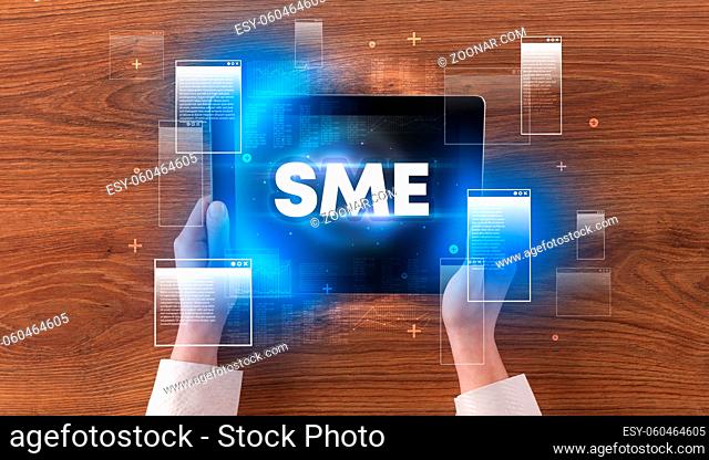 Close-up of a hand holding tablet with SME abbreviation, modern technology concept