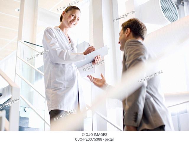 Businessman talking to scientist on office staircase