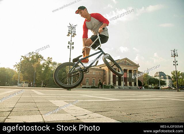 Young BMX biker doing stunt at Hero's Square, Budapest, Hungary