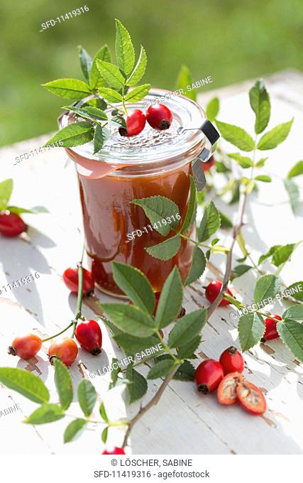 A jar of homemade rosehip jelly on a garden table