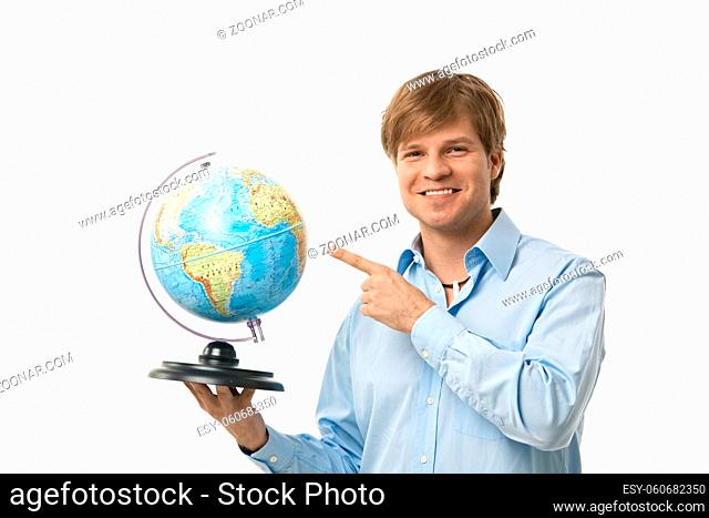 Happy young man pointing to globe in his hand, smiling. Cutout