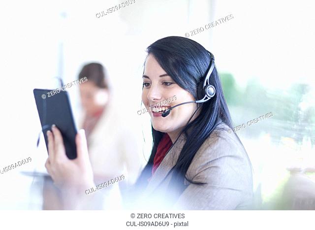 Businesswoman using digital tablet and having telephone conversation on headset