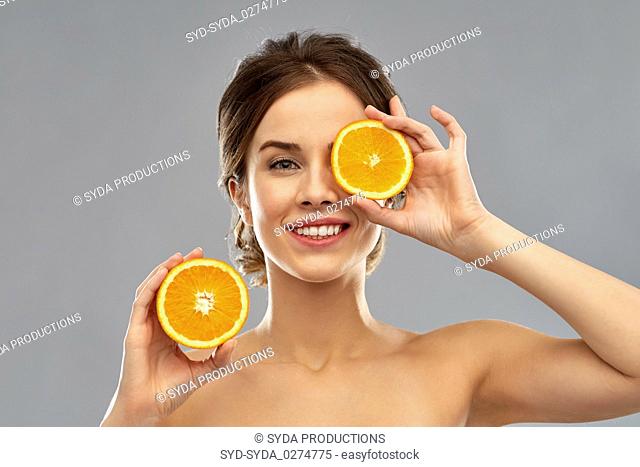 smiling woman with oranges over grey background