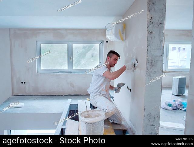 young professional construction worker plastering on gypsum walls inside the new big modern two levels apartment