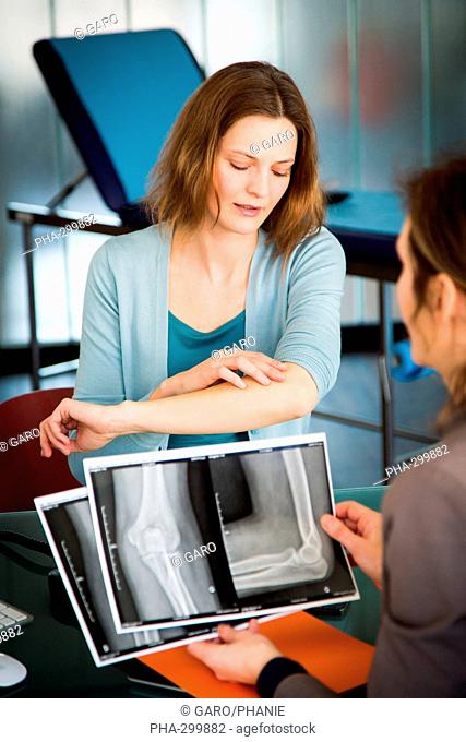 Doctor examining and commenting patient's elbow X-ray