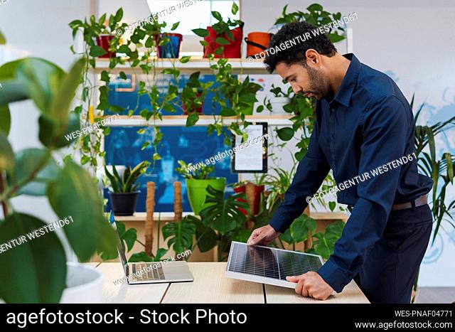 Businessman in office looking at solar panel