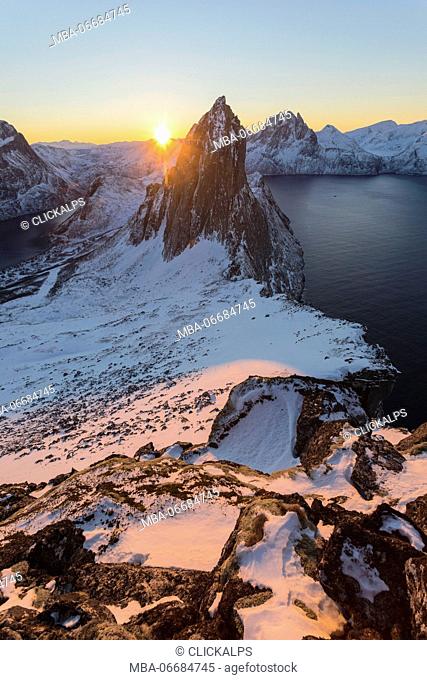 First lights of sunrise on Mount Segla and Mefjorden framed by the frozen sea seen from peak Hesten Senja Tromsø Norway Europe