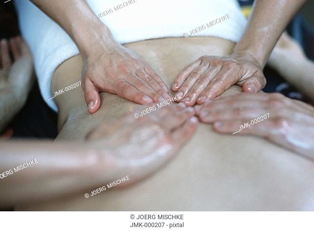 physical therapist, two physical therapists, is giving, are giving, a massage to a young man