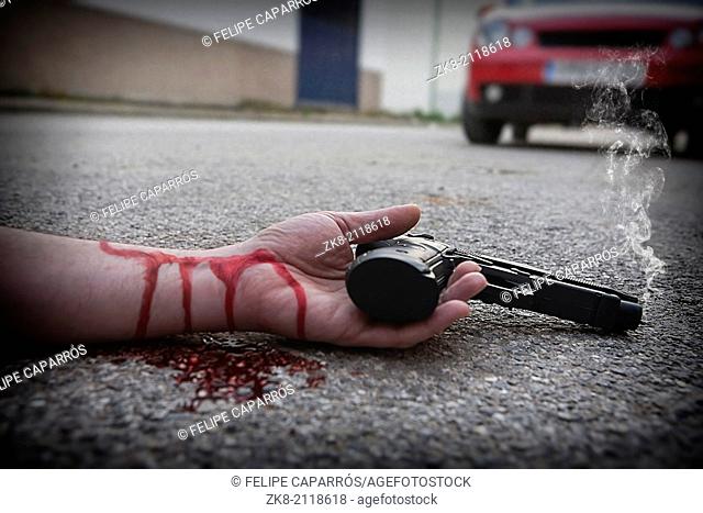 Man with gun in hand bloodstained lies dead in the asphalt murder victim